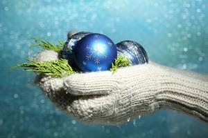 Female hands in mittens Christmas tree balls, on color background