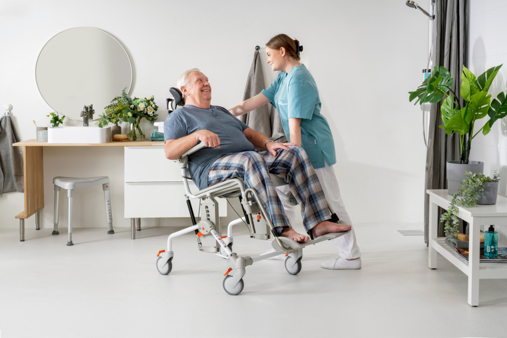 Etac Swift Mobil Tilt-2 - kallistettava suihkutuoli XL - mies ja hoitaja